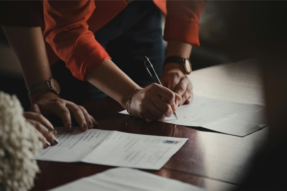 Two people signing documents together